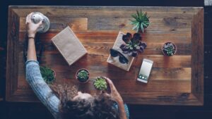 Woman arranging plants on a wooden table.