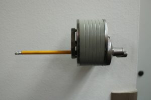 Crayon tenu avec précision dans un dispositif mécanique, illustrant notre expertise en dépannage volet roulant Villeneuve d'A