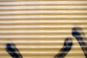 Rideau métallique doré avec des traces de graffiti sombres.