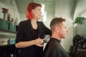 Coiffeur professionnel coupant les cheveux d'un client dans un salon.