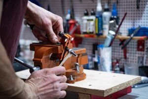 Mains d'un artisan utilisant un étau de menuiserie dans un atelier.