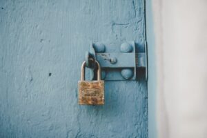 Verrou rouillé sur une porte en bois bleu délavé.