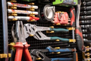 Outils et accessoires de bricolage rangés sur un panneau perforé.