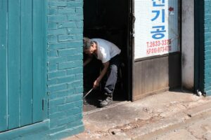 Homme assis dans l'encadrement d'une porte, dans une ruelle.