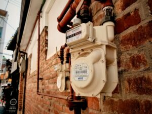 Compteur de gaz naturel installé sur un mur de briques.