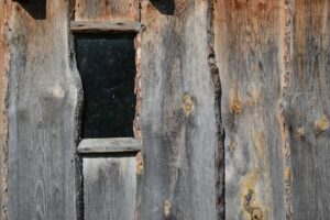 Vieille porte en bois rustique avec une ouverture sombre.