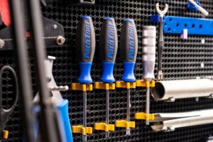 Outils de bricolage bleus et dorés rangés sur un panneau perforé.