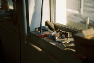 Outils de bricolage éparpillés sur une surface sombre près d'une fenêtre.