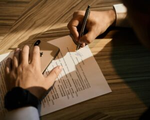Signature manuscrite sur un document sur un bureau en bois.