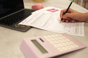 Formulaire de demande rempli à la main avec calculatrice et ordinateur portable.