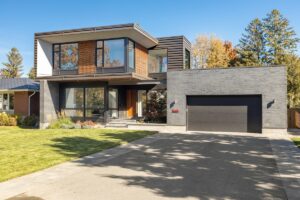 Maison moderne en briques grises avec toit en surplomb et garage.